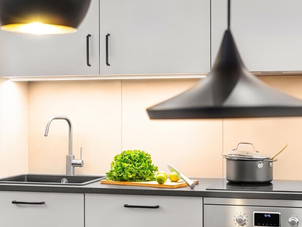 Une cuisine moderne avec un évier, une planche à découper avec des légumes, un couteau et une casserole sur la cuisinière.
