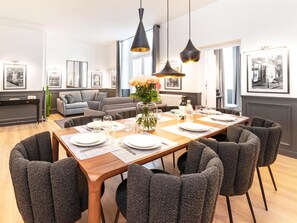 A dining area with a wooden table set for six, surrounded by six grey upholstered chairs.