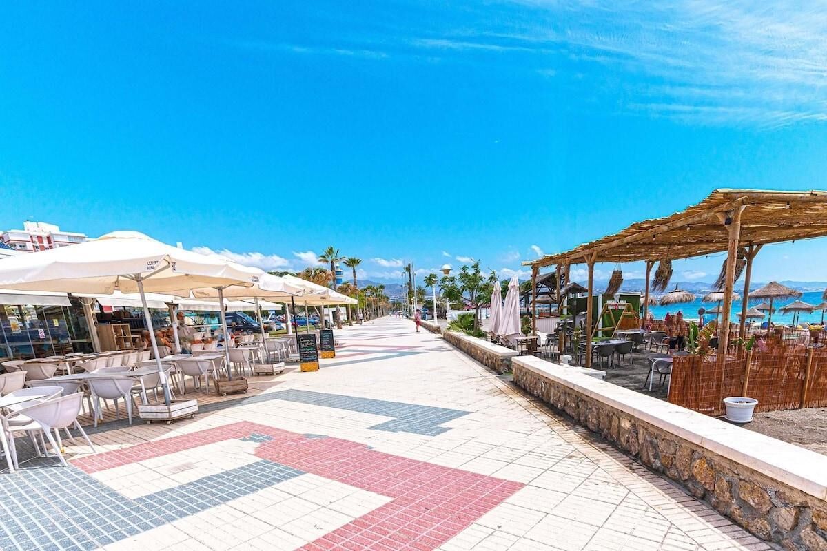 Un café situé en bord de mer, avec une terrasse, des parasols et une vue sur l’océan.