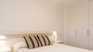 Een slaapkamer met een bed, bedlampen, een nachtkastje en een kledingkast.