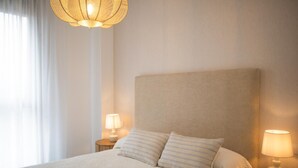 Una habitación de hotel con una cama grande, dos lámparas de noche y una lámpara colgante.