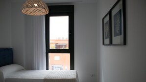 Un dormitorio con cama, ventana y lámpara colgante.
