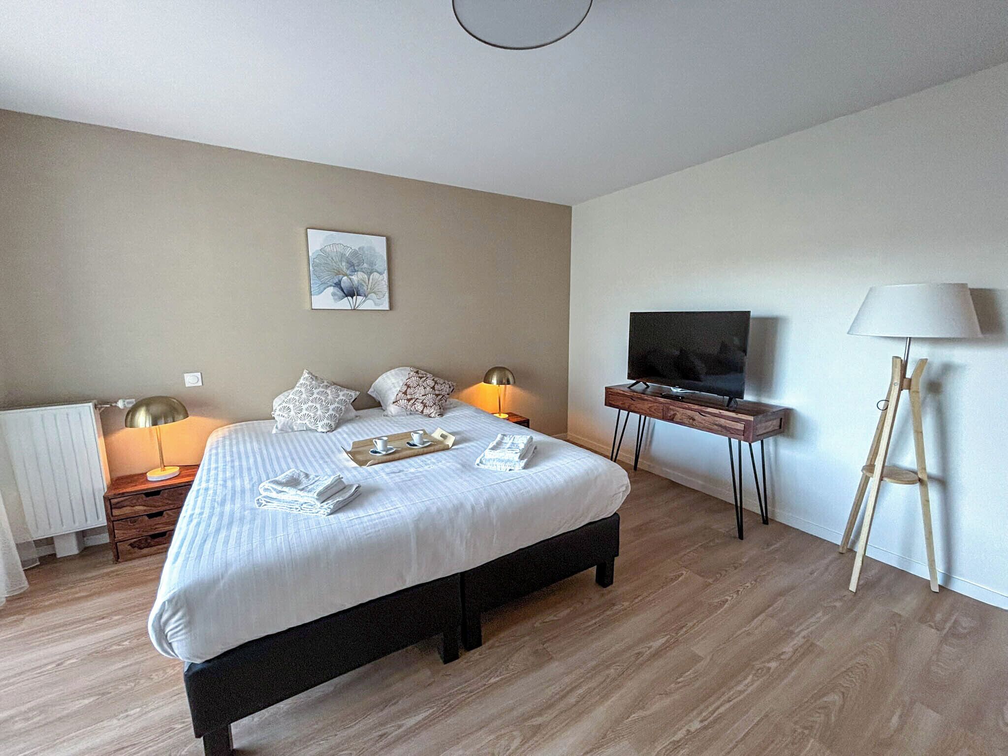 Ein modernes Hotelzimmer mit einem großen Bett, Nachttischlampen, einem Flachbildfernseher und einem Holzboden.