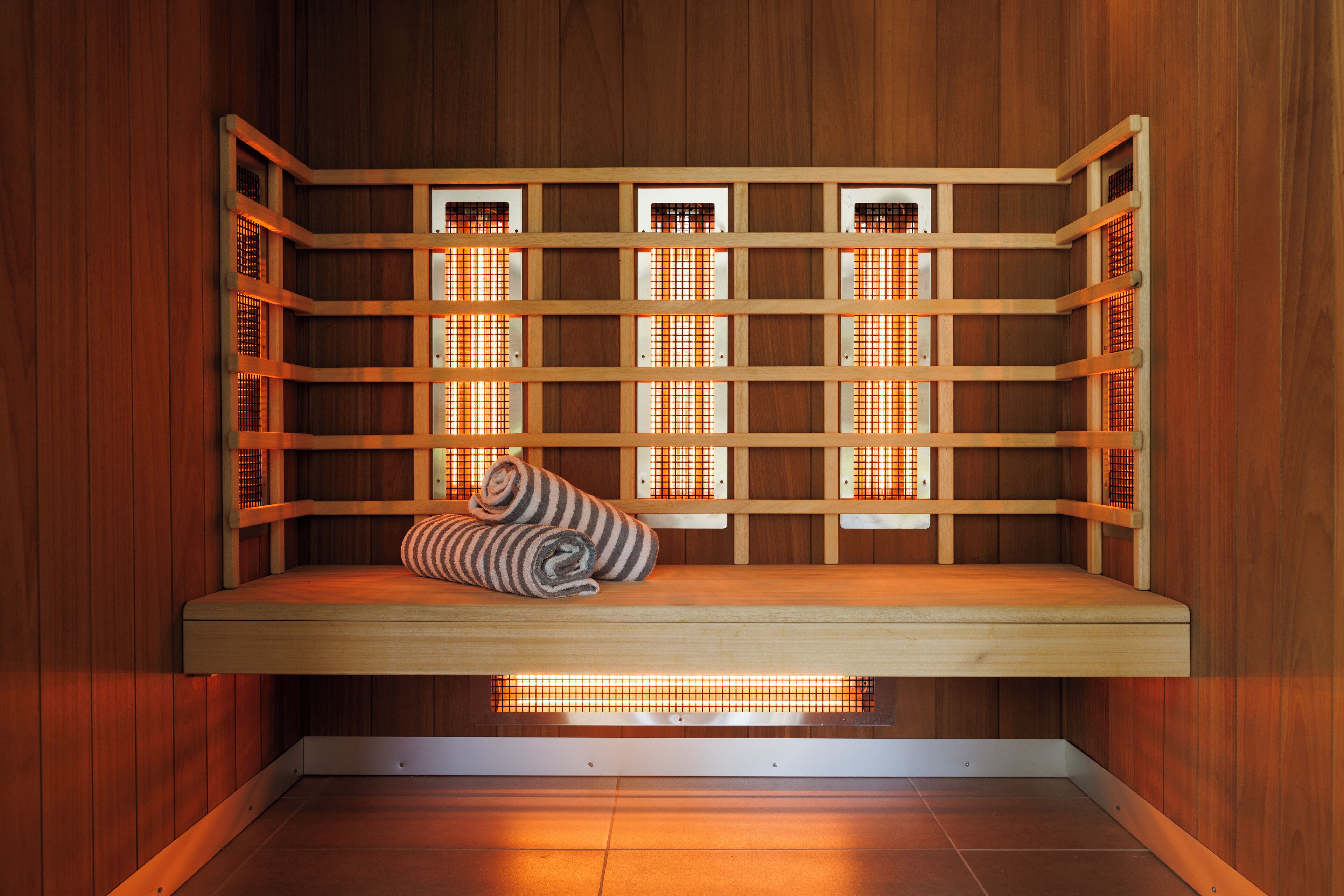A wooden sauna with a bench and a towel.