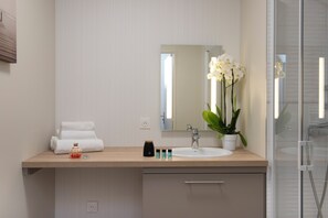 Een moderne badkamer met een houten wastafel, een grote spiegel, een witte wasbak en een potorkidee.