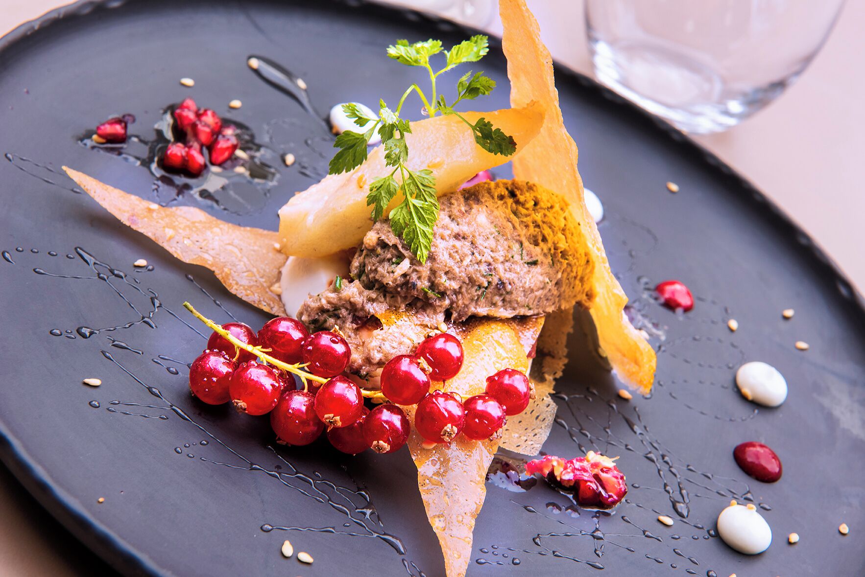 Une assiette à dessert avec une tranche de pain, des groseilles rouges et une décoration de feuilles de menthe.