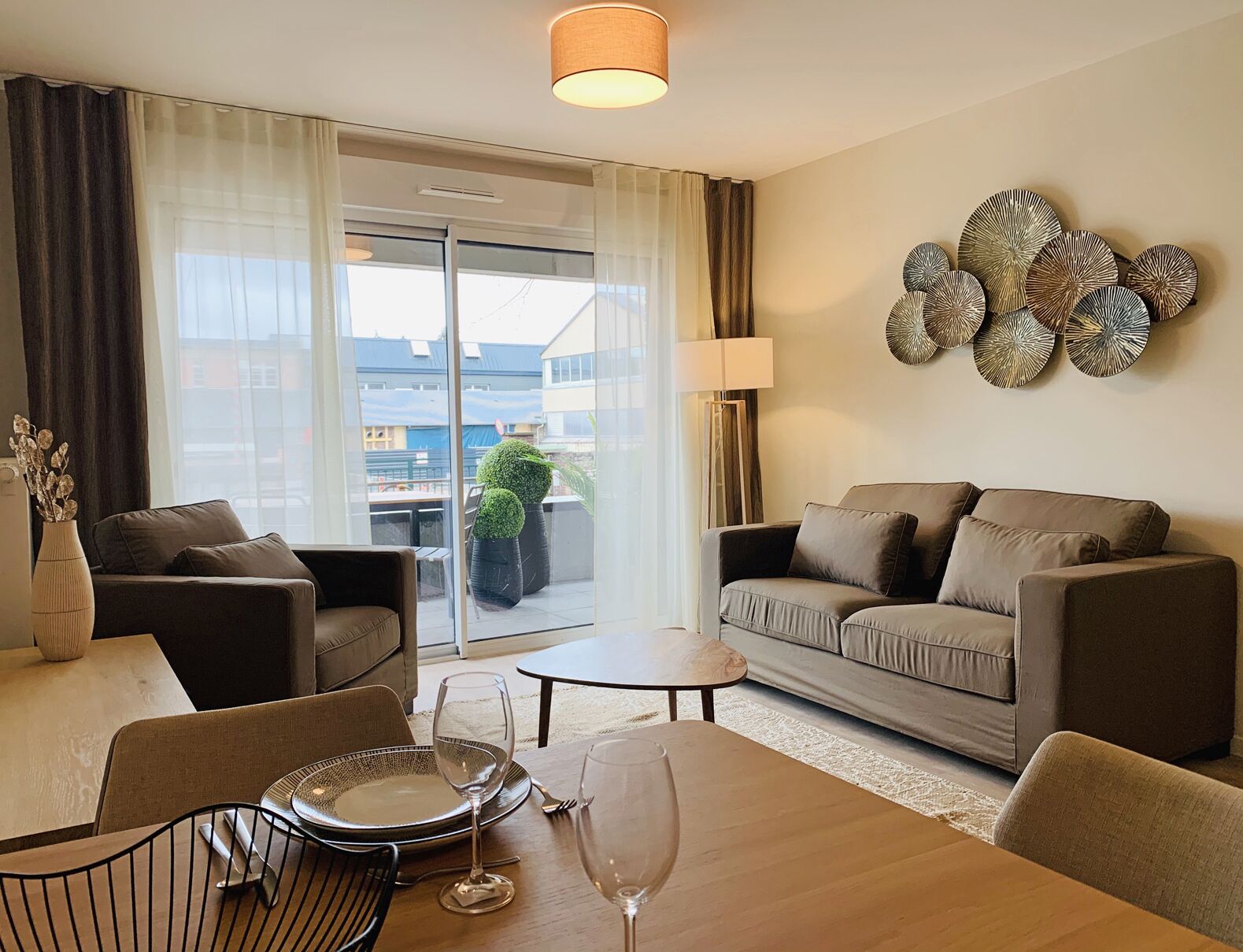 A modern living room with a sofa set, a dining table with chairs, and a decorative wall piece.
