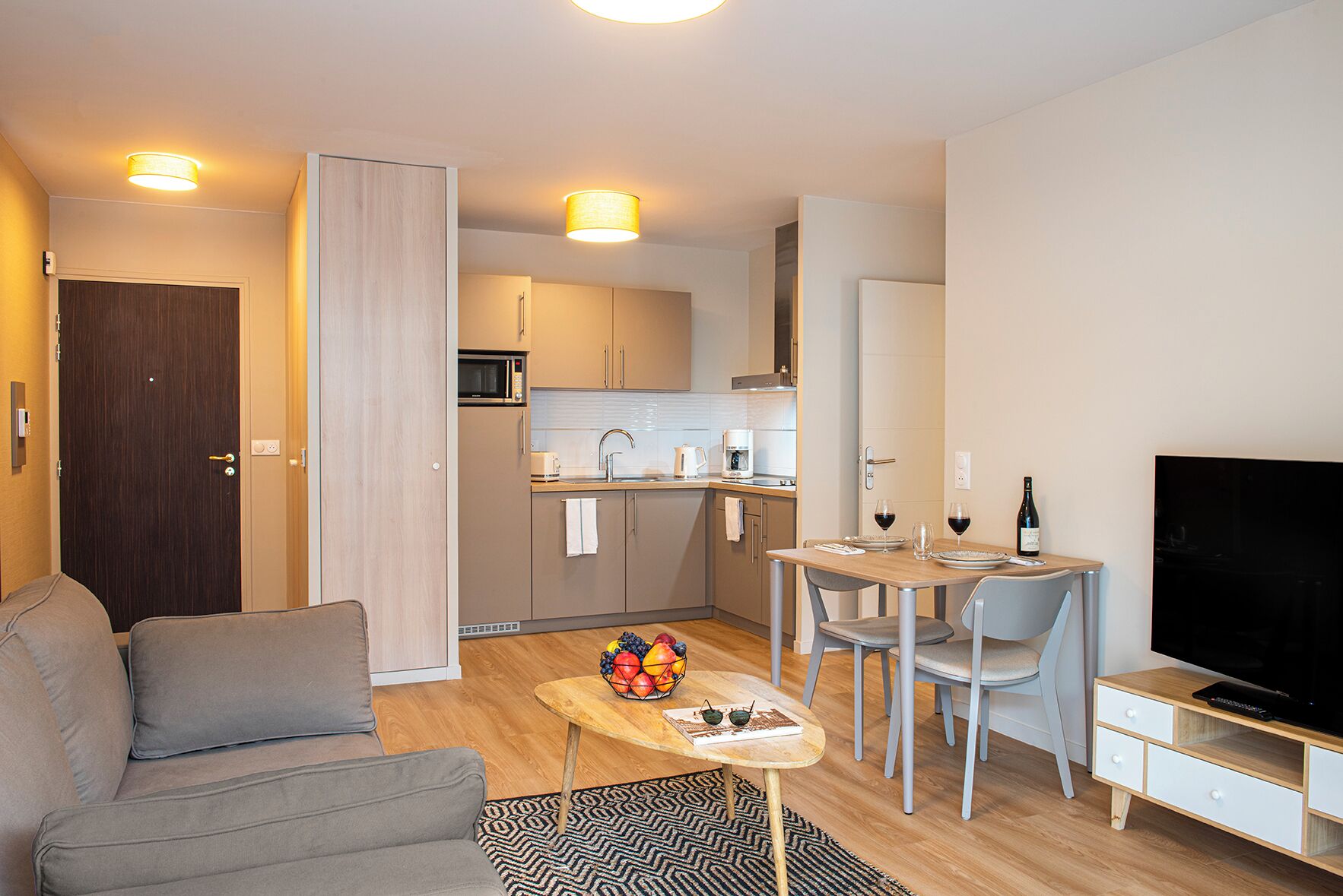 A modern apartment with a living room, dining area, and kitchen.