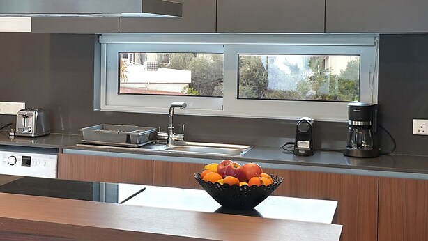 Una cocina moderna con horno empotrado, cafetera y frutero sobre la encimera.