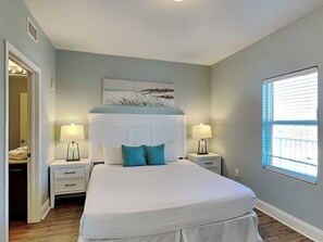 A bedroom with a large bed, two bedside tables with lamps, a window with blinds, and a door leading to a closet. - Laketown Wharf #913 | Beautiful Condo, Stunning View + Resort Amenities (Panama City Beach)