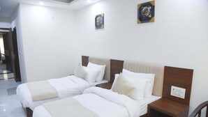 Camera d'albergo con due letti, una testiera in legno, un comodino e una presa elettrica a muro.