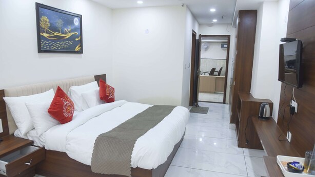 Una camera d'albergo con un letto, una TV, una scrivania in legno e un bagno visibile attraverso una porta aperta.