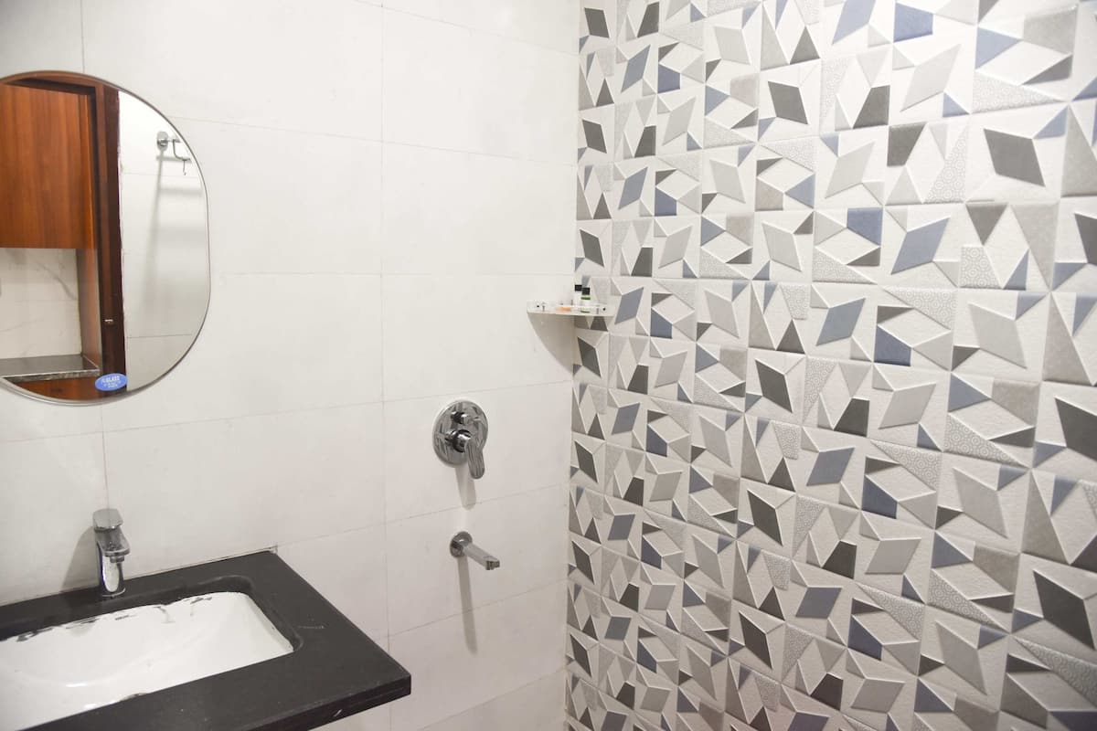 A bathroom with a black sink, a mirror, and a geometric-patterned wall.