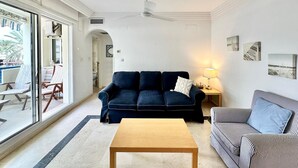 A living room with a dark blue sofa, a striped sofa, a wooden coffee table, and a floor lamp.