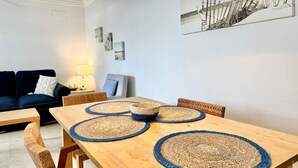 A dining area with a wooden table, blue and beige woven placemats, wicker chairs, and a hanging light fixture.