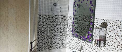 A bathroom with a sink, mirror, and shower area.
