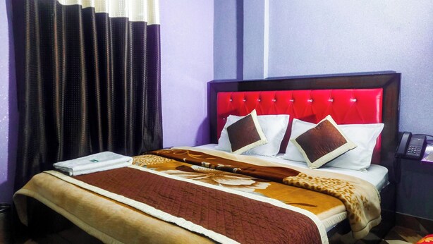 Une chambre d’hôtel avec un lit, une table de chevet, un téléphone et un rideau.