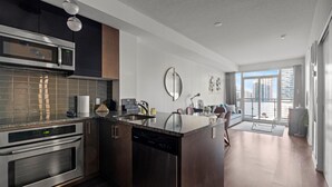 A modern kitchen with stainless steel appliances, a central island, and a dining area with a view of the city. - GLOBALSTAY Modern 1BD+Den Condo w/ Balcony Lillian St (Toronto/Canada)
