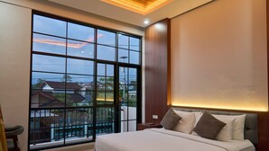 A bedroom with a large window, a bed with pillows, and a nightstand. - Sakanti Inn Wonosobo (Wonosobo)