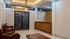 A modern living room with a wooden dining table, a chandelier, and a decorative wall panel. - Sakanti Inn Wonosobo (Wonosobo)