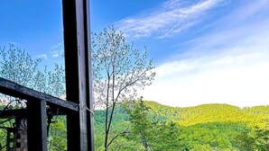 A rustic wooden deck overlooking a lush green landscape with a small house and a river.