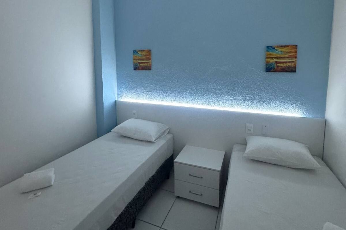 Ein Zimmer mit zwei Einzelbetten, einem kleinen Nachttisch und einem Beistelltisch.