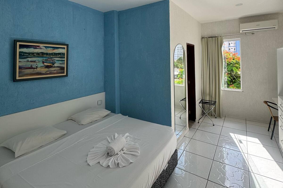 Ein Hotelzimmer mit Bett, einem Gemälde und Blick nach draußen.