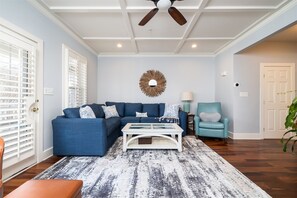 Ein Wohnzimmer mit Ecksofa, Couchtisch, Deckenventilator und Wanddekoration.