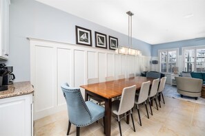 Un coin repas avec une table et des chaises en bois, un mur recouvert de panneaux blancs et des tableaux encadrés accroch és au-dessus.
