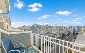 Ein Wohngebiet mit mehreren Häusern, einem Balkon mit Stuhl und blauem Himmel.