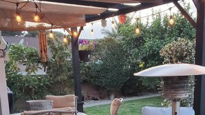 Une terrasse extérieure avec une table et des chaises, un radiateur et des plantes en pot.
