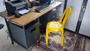 Un espacio de trabajo compacto con escritorio, computadora, impresora y una silla amarilla.