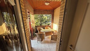 Ein Patio mit einer Ziegelwand, einer Holzbeschichtung und einer Glastür, die nach draußen führt.