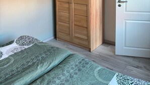 Ein Schlafzimmer mit einem Holfischschrank, einem Bett mit gemusterten Betttextilien und einer weißen Tür.