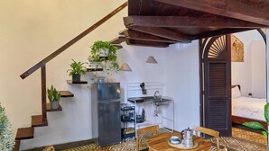 A cozy room with a patterned floor, a wooden table with chairs, a ceiling fan, and a staircase with plants.