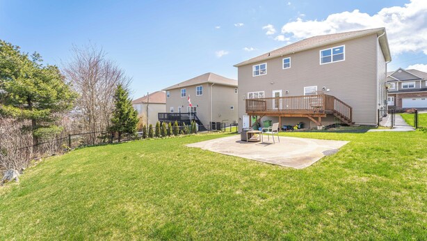 Una zona residencial con dos casas, un patio cubierto de césped y una terraza de madera.