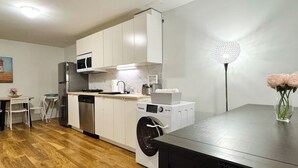 Una cocina moderna con armarios blancos, lavavajillas, lavadora y microondas.