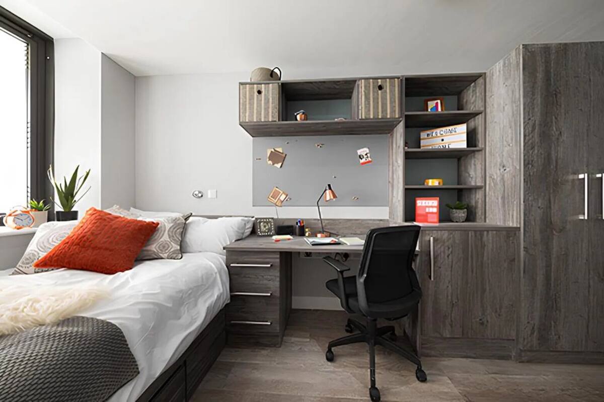 Une chambre à coucher comprenant un lit, un bureau, une chaise, une armoire et des étagères.