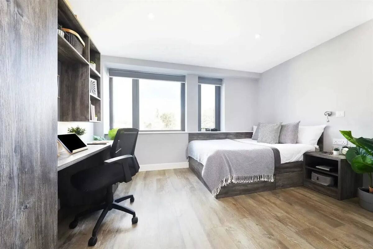 Une chambre moderne avec un bureau, un lit et une fenêtre.