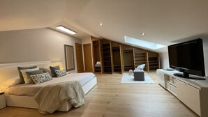 Ein modernes Schlafzimmer mit einem großen Bett, einem Fernseher und einem begehbaren Kleiderschrank.