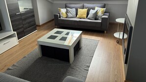 Ein modernes Wohnzimmer mit einem grauen Sofa, einem Glastisch und einem Oberlicht.