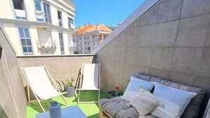 Eine Dachterrasse mit einer hölzernen Bank, einem kleinen Tisch und einem Blumentopf.