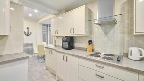A modern kitchen with white cabinets, a built-in oven, a coffee machine, and a kettle. - Host & Stay | Sea Haven (Redcar)