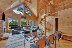 A spacious living area with a modern fireplace, a glass dining table, and a comfortable seating arrangement. - Cabin with Gorg Mtn View~4 BR~4 Baths~3 mi to Pigeon Frg Pkwy~ (Sevierville)