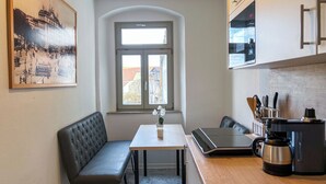 A compact kitchen with a dining area, a large window, and a view of the street. - Central apartment for 4 people with kitchen, WiFi & private parking space (Meißen)