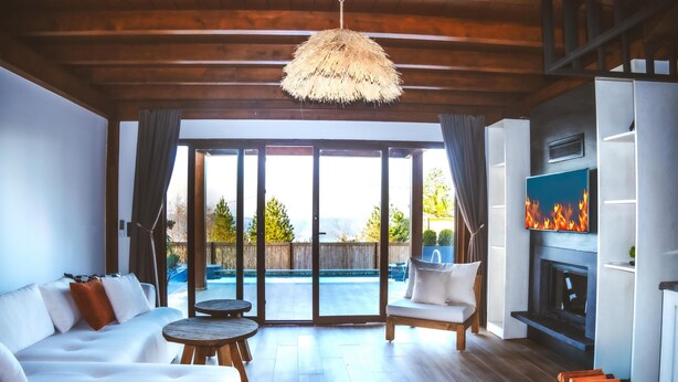 A modern living room with a sofa, a round table, a fireplace, and a large sliding glass door leading to a pool. - Exclusive Hill Sapanca (Sapanca)