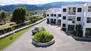 A modern building with a central circular garden, surrounded by a paved area and a road. - san rocco one bed apartments   1b1 4 (ISCA SULLO IONIO)