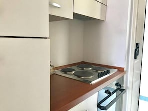 A compact kitchen with a stove, oven, and a refrigerator.