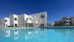 A swimming pool with a modern building in the background. - san rocco one bed apartments   1b1 4 (ISCA SULLO IONIO)