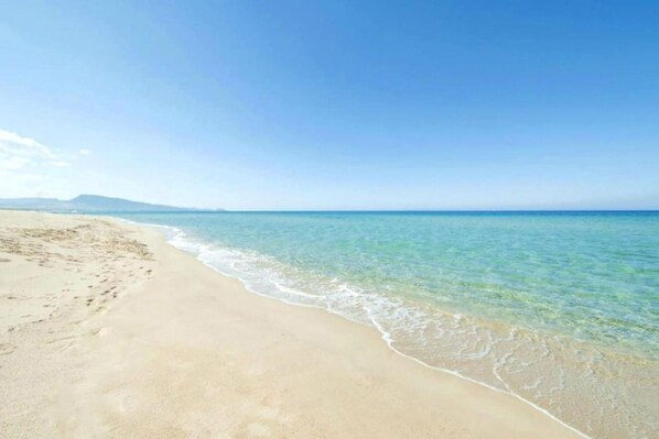 A beach with clear water and a sandy shore.